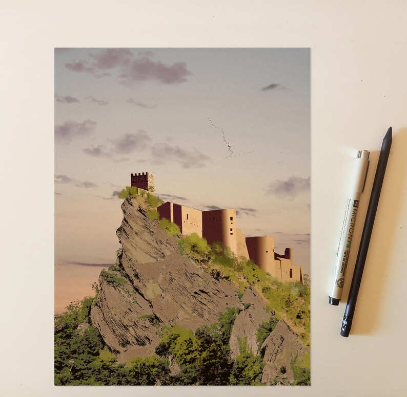 May include: A rectangular art print depicting a castle perched atop a jagged, rocky cliffside with green vegetation, set against a soft sunset sky with scattered clouds. A white fine-liner pen and a black pencil are positioned to the right.