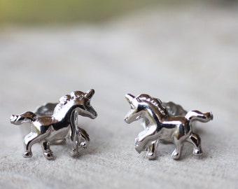 May include: A pair of silver unicorn stud earrings. The unicorns are facing each other and have a detailed design.