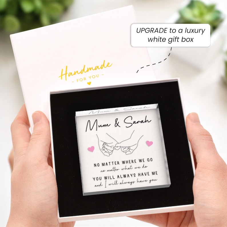 May include: A white gift box with a black interior holds a square glass block. The block features the text "Mum & Sarah" and a line drawing of two hands holding pinky fingers. The box is labeled "Handmade - FOR YOU".