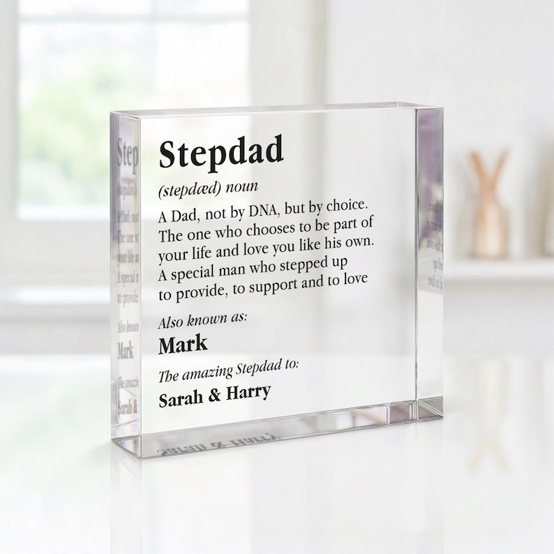 May include: A clear acrylic block with the word "Stepdad" and a definition printed in black. The definition includes the phrases "A Dad, not by DNA, but by choice" and "Also known as: Mark". The names "Sarah & Harry" are also printed on the block.
