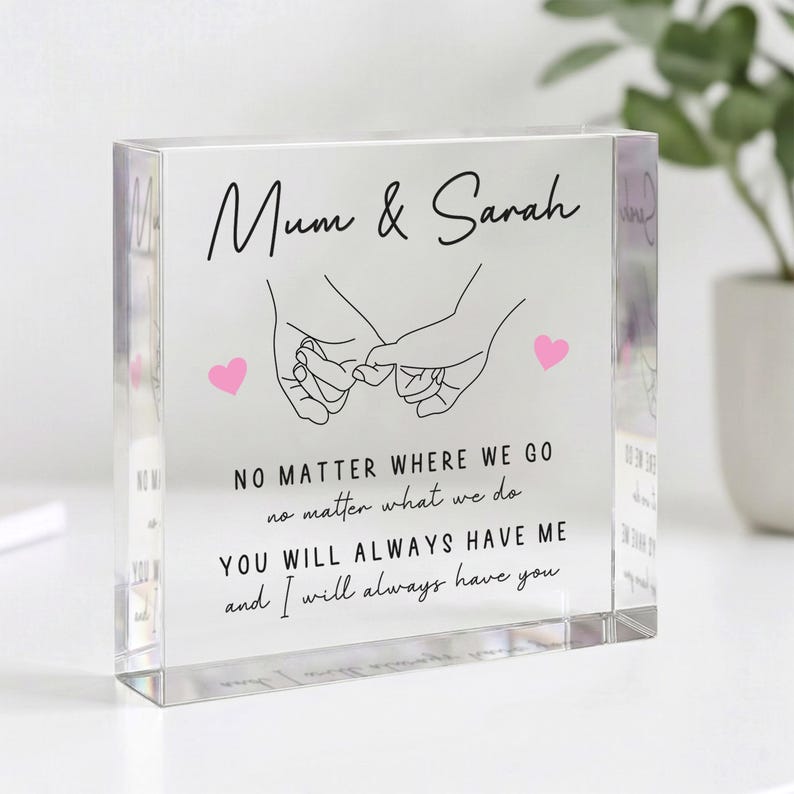 May include: A clear acrylic block with the text "Mum & Sarah" and a line drawing of two hands holding pinky fingers. Below the names is the text "NO MATTER WHERE WE GO...YOU WILL ALWAYS HAVE ME and I will always have you."