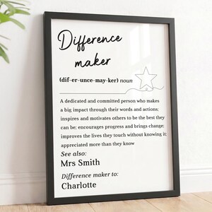 May include: A black framed wall art print featuring the dictionary definition of the term Difference maker. The text includes the phonetic spelling, a star icon, and a descriptive paragraph, followed by the names Mrs Smith and Charlotte.