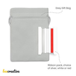 May include: A grey gift bag with a silver drawstring next to a ribbon pack. The ribbon pack includes silver, white, and red ribbons. The image also includes the text "beecreative".