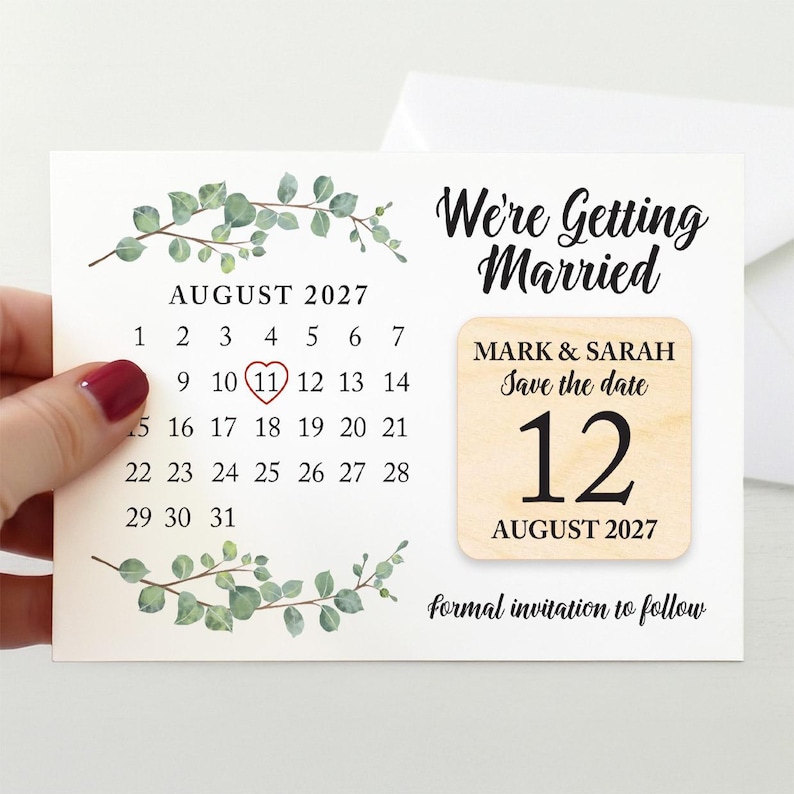 May include: A wedding save-the-date card with an August 2027 calendar, circled on the 11th. The card reads "We're Getting Married" and includes a wooden accent with the names "Mark & Sarah" and the date "12 August 2027". The design is decorated with green leaves.