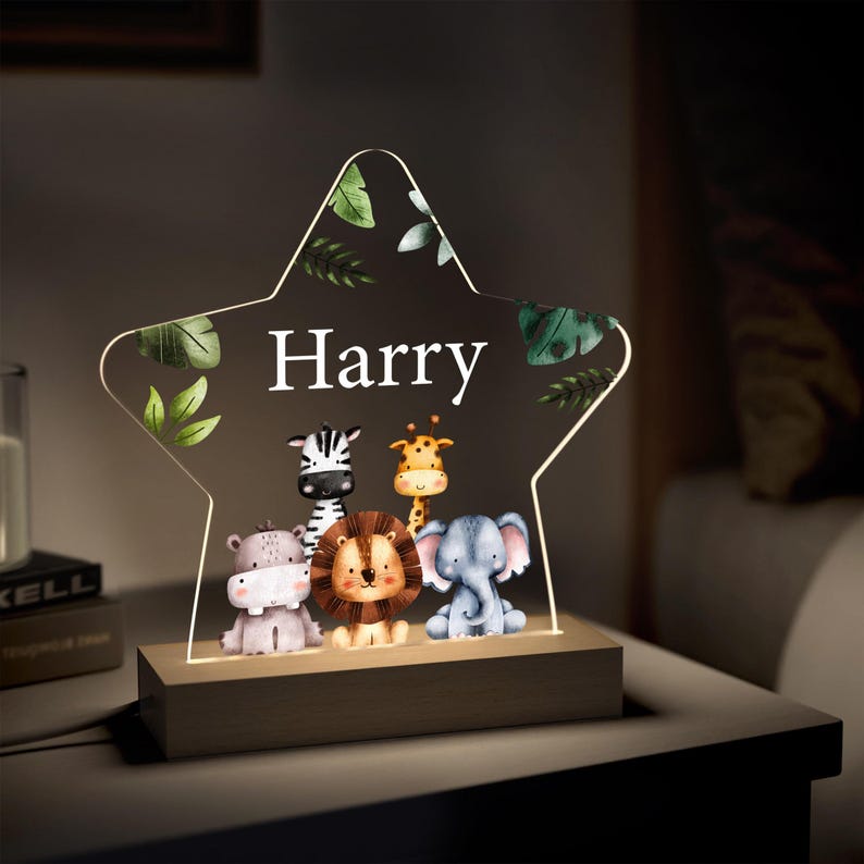 以下が含まれることがあります： 「Harry」の名前とシマウマ、キリン、ライオン、ゾウ、カバのイラストが描かれた星型のナイトライト。木製のベースと、緑の葉の模様が入った透明なアクリル製の前面を備えています。