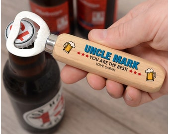 May include: A wooden bottle opener with a metal opener, opening a beer bottle. The handle is light-coloured wood with the text "UNCLE MARK YOU ARE THE BEST! LOVE SARAH" in blue, with beer mug graphics and red stars.