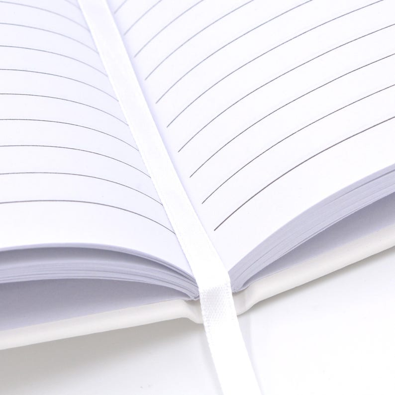 An open white notebook with lined pages, secured by a white ribbon.
