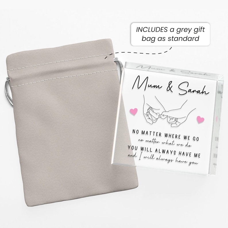 May include: A clear acrylic block with the words "Mum & Sarah" and a line drawing of two hands holding pinky fingers. The block also has the text "NO MATTER WHERE WE GO..." and is accompanied by a grey gift bag.