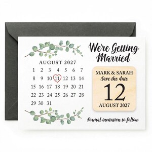 May include: A wedding save-the-date card with a calendar design for August 2027. The card features the text "We're Getting Married" and "Save the date 12 August 2027". The card is decorated with green foliage and comes with a dark grey envelope.