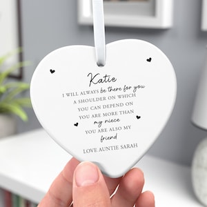 May include: A white heart-shaped ceramic ornament featuring black printed text that reads: Katie, I WILL ALWAYS be there for you, A SHOULDER ON WHICH YOU CAN DEPEND ON, YOU ARE MORE THAN my niece, YOU ARE ALSO MY friend, LOVE AUNTIE SARAH.