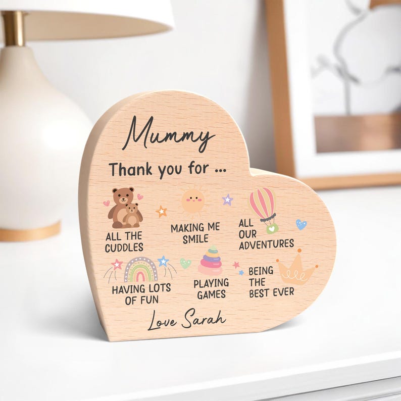 K&ouml;nnte beinhalten: Herzf&ouml;rmige Holzplakette mit dem Wort "Mummy" oben. Die Plakette tr&auml;gt den Text "Thank you for..." und enth&auml;lt Illustrationen und S&auml;tze wie "All the cuddles" und "Love Sarah."