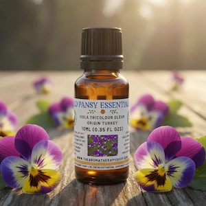 Könnte beinhalten: Eine braune Glasflasche mit Wild Pansy Essential Öl, 10 ml, mit braunem Deckel, auf einer Holzoberfläche. Das Etikett trägt die Aufschrift "Wild Pansy Essential" und "Viola Tricolour Oleum". Veilchen mit violetten, gelben und weißen Blüten umgeben die Flasche.