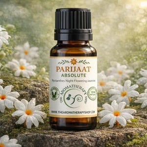 Puede incluir: Una botella de vidrio marrón con tapa negra, etiquetada "Parijaat Absolute" con texto sobre aromaterapia y jazmín. La botella está rodeada de flores blancas con centros naranjas, sobre una superficie musgosa.