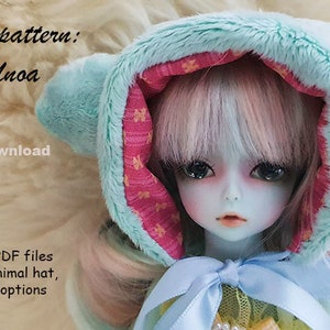 Op de afbeelding: Een lichtblauwe dierenmuts met roze en gele geprinte voering en harige oren. De muts wordt gedragen door een pop met roze en blauw haar. De tekst "Tsukifly PDF pattern: Yo-SD|Tiny|Unoa Animal hat Instant download Pattern suitable for 6-7 inch dolls' head Yo-SD, Tiny and Unoa Listing includes instantly downloable PDF files with pattern for an animal hat, three alternative ear options + written instructions" is zichtbaar in de afbeelding.