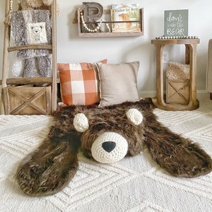 Plush Bear Rug on floor in kid room. With pillows and blanket ladder. Dont wake the bear sign hanging on the wall and wooden book shelf with books hanging under faux deer taxidermy