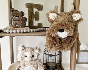 May include: A wooden shelf with a brown teddy bear, a wooden letter E, a brown plush reindeer, a brown owl, a glass lantern, a wooden hedgehog, and a sign that says "goodnight".