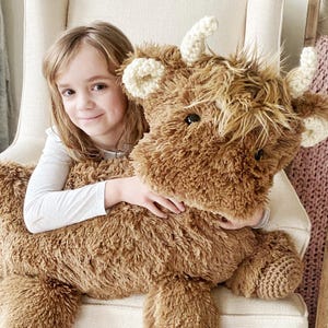 Peluche di mucca Highland marrone con pelliccia sintetica e dettagli all'uncinetto per la cameretta dei bambini.