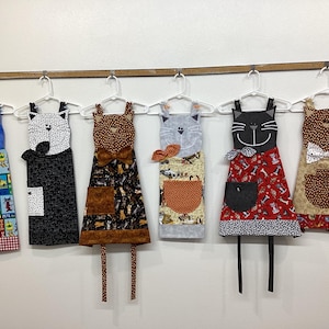 Cat child apron, crazy cat apron, cats, kitties, animal face, whiskers, bows, red, black, gray, orange, brown, dots, plaid, pocket, bookmark