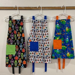 Child&#39;s apron, Bugs, Reptiles, Robots, frogs, beetles, blue, black, orange, green, Front pocket, lining. For boys or girls. Reversible.