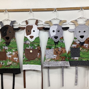 Goats child's apron, crazy goats, horns, beard, smile, green, brown, white, patch, animal face, pocket, buttons, cooking painting, bookmark