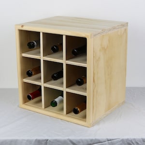 May include: A wooden wine rack with 12 compartments for storing wine bottles. The rack is made of light-colored wood and has a simple, modern design.
