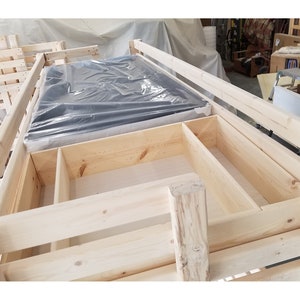 May include: A wooden bunk bed frame with a mattress in the top bunk. The frame has built-in storage shelves and drawers.