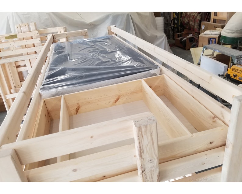 May include: A wooden bunk bed frame with a mattress in the top bunk. The frame has built-in storage shelves and drawers.