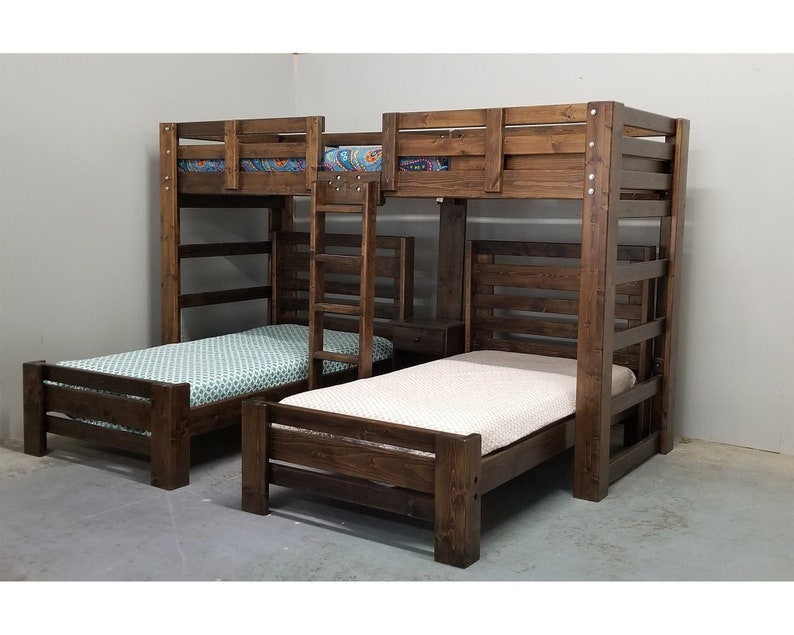 May include: A wooden bunk bed with a ladder and a single bed on the bottom. The bunk bed is stained a dark brown colour. The bed is made with a white and a blue patterned sheet.