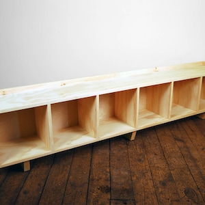 May include: A wooden shelf unit with five open compartments. The shelf is made of light wood and has a natural finish.