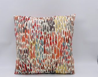 May include: A decorative throw pillow with a colorful abstract pattern featuring shades of red, orange, yellow, blue, and gray. The pattern resembles a watercolor design with irregular shapes and lines.