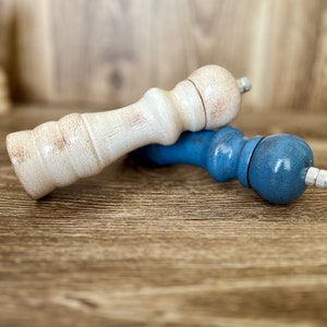 Puede incluir: Dos saleros y pimenteros, uno blanco y otro azul, sobre una superficie de madera.