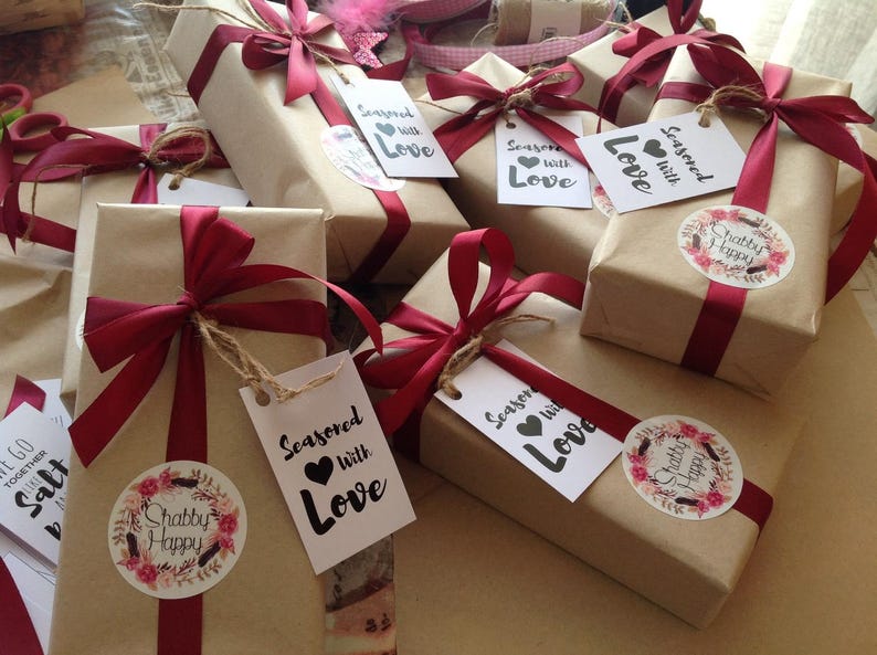 May include: Multiple brown paper gift boxes tied with red ribbon and decorated with tags that say "Seasoned with Love" and "Shabby Happy".