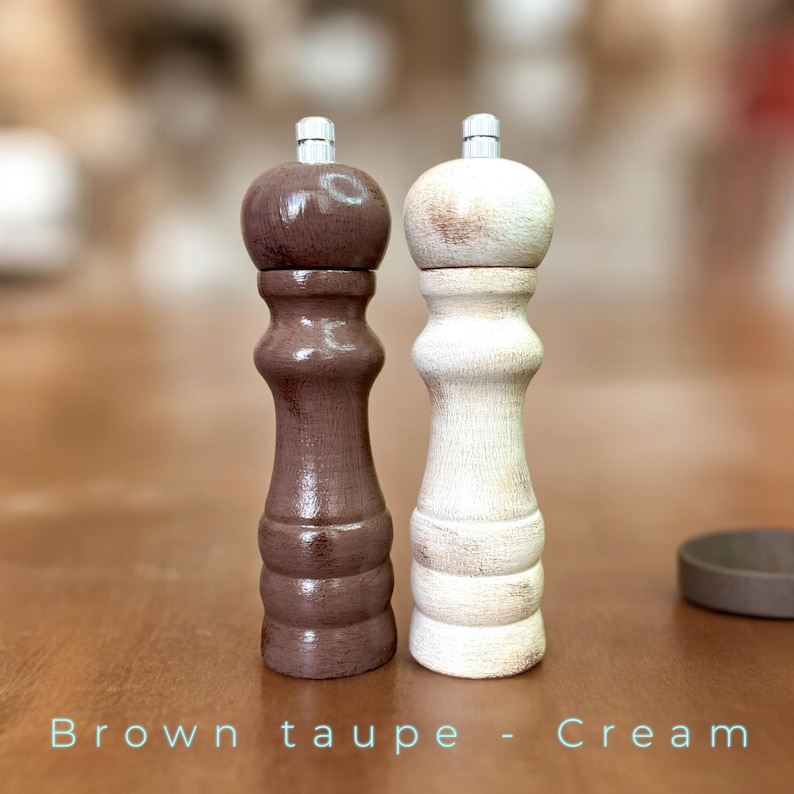May include: Two wooden salt and pepper shakers, one brown taupe and one cream, with a distressed finish.