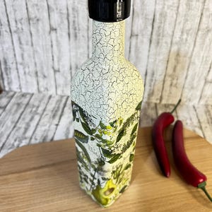May include: A white ceramic bottle with a black lid and a floral design. The bottle is sitting on a wooden surface.
