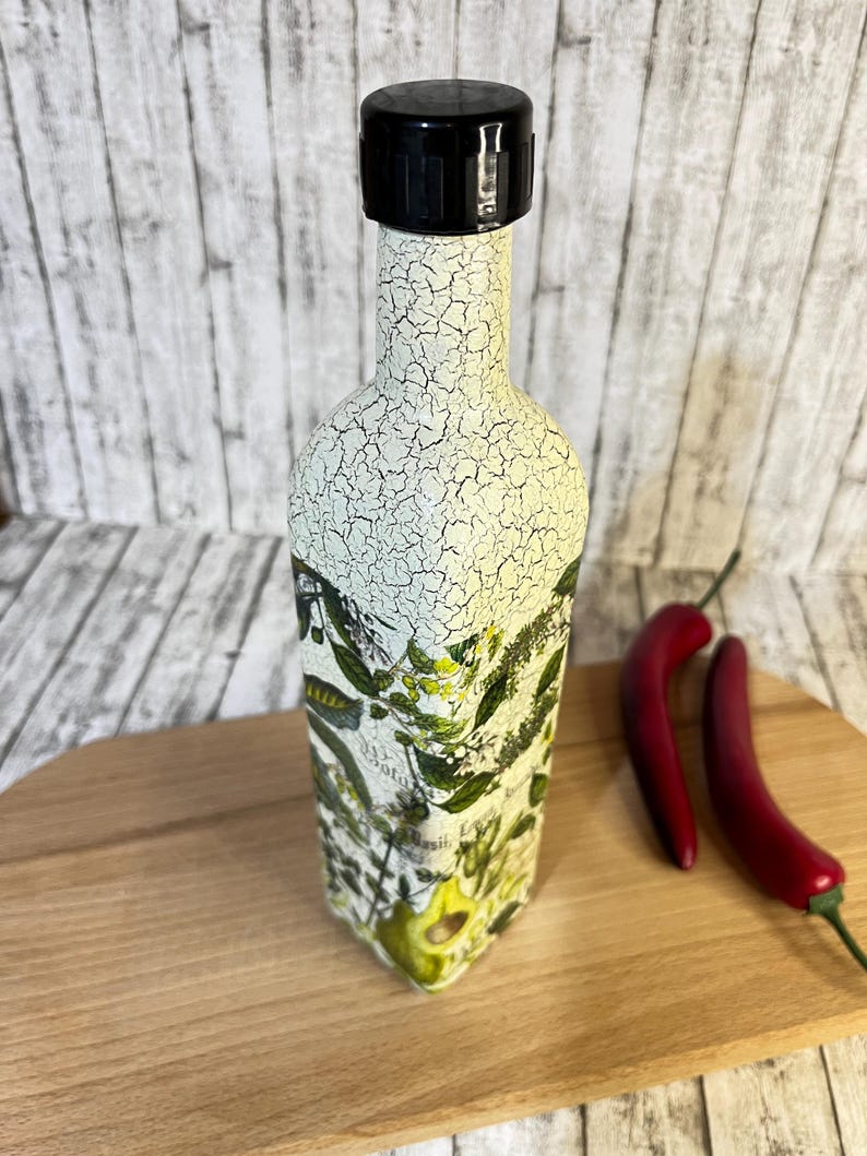 May include: A white ceramic bottle with a black lid and a floral design. The bottle is sitting on a wooden surface.