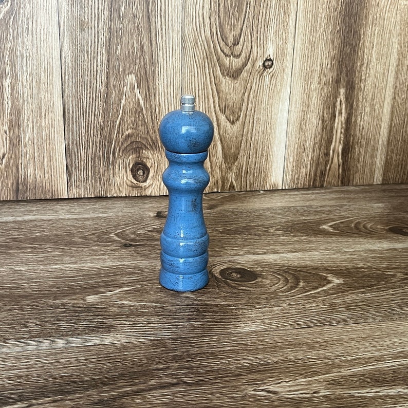 Puede incluir: Un molinillo de sal y pimienta de madera azul con un acabado desgastado.