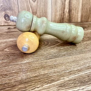 May include: A set of two wooden salt and pepper shakers. The salt shaker is yellow and the pepper shaker is green. Both shakers have a distressed paint finish.