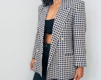 Könnte beinhalten: Ein schwarz-weiß karierter Blazer mit doppelreihigem Verschluss. Der Blazer hat eine klassische Passform und einen Schalkragen.