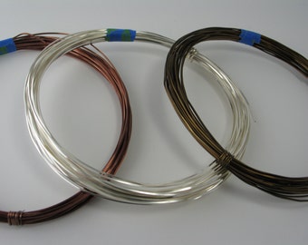 May include: Three spools of wire, one silver, one copper, and one bronze. The spools are wrapped in blue tape.