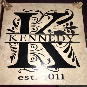 May include: A beige tile with a black decorative letter K with a black banner across the middle that reads "KENNEDY" and the text "est. 2011" below.