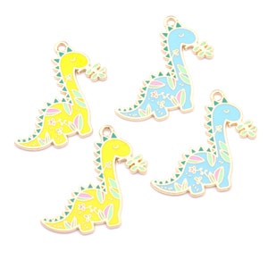 May include: Four gold-tone dinosaur charms with enamel paint. Two are yellow with green and pink floral designs and two are blue with green and pink floral designs.