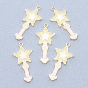 May include: Six gold-colored metal charms shaped like a star-topped wand. Each charm has a white star with a gold outline and a pink wand with a gold outline.