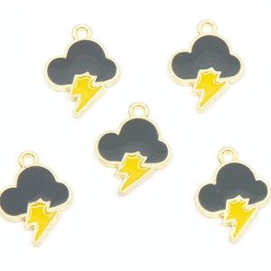 May include: Five gold-toned charms featuring a black cloud with a yellow lightning bolt. The charms have a gold border and a small loop at the top for attaching to jewelry or other crafts. The charms are designed to look like a storm.