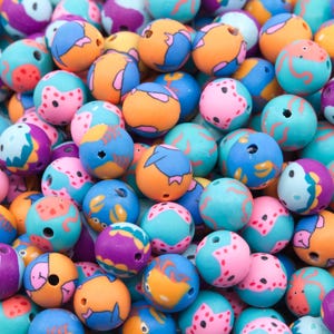 May include: A collection of colorful wooden beads with various sea creature designs. The beads are round and have a smooth, glossy finish. The designs include starfish, seahorses, and fish.