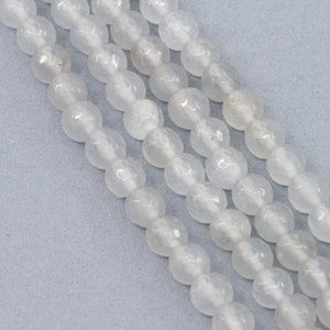May include: A strand of white, translucent, round beads. The beads have a slightly textured surface.