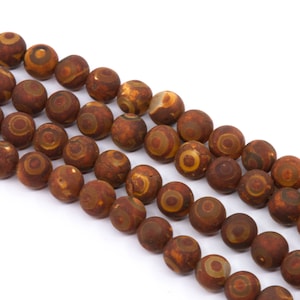 May include: A strand of brown agate beads with a swirling pattern of yellow and white. The beads are round and smooth.