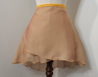 Può includere: Una gonna da ballo in chiffon color pesca pallido con una cintura gialla. La gonna ha un orlo arricciato ed è esposta su un manichino di legno.