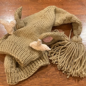 May include: A knitted brown deer hat with a long tassel and white felt antlers.