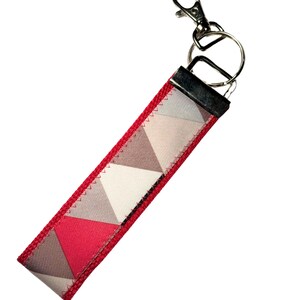 May include: A red and gray geometric patterned key chain with a silver key ring.
