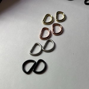 May include: A set of eight metal D-rings in various finishes, including gold, rose gold, silver, and black.